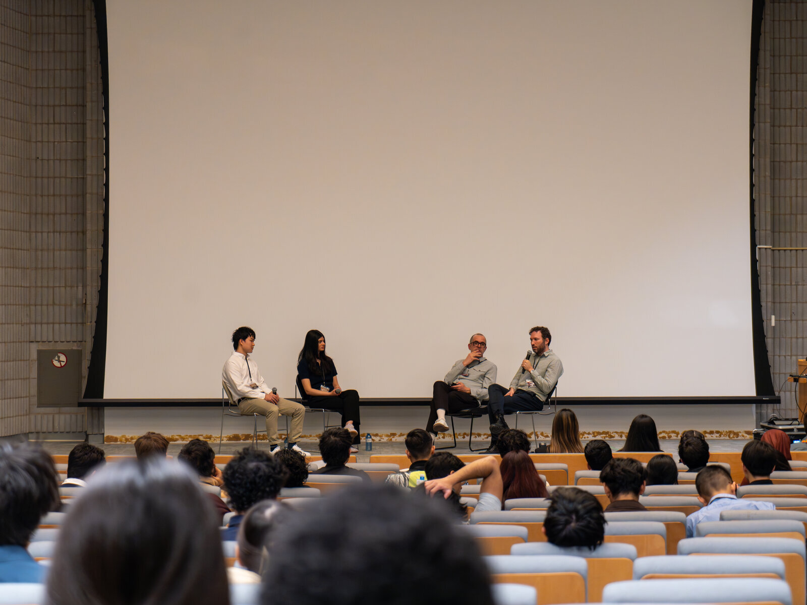 Audience view of a panel discussion in a lecture hall.